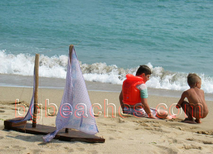 Children are playing on the beach of Karadere. There is a home made made yacht next to them.