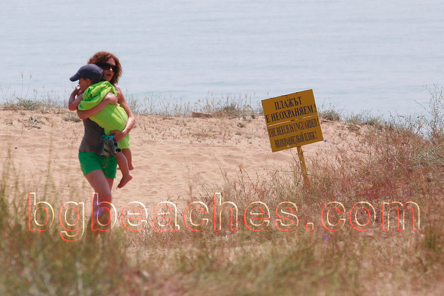 Тази табела ни информира, че плажът е неохраняем. Как смее тази млада майка да води детето си там.